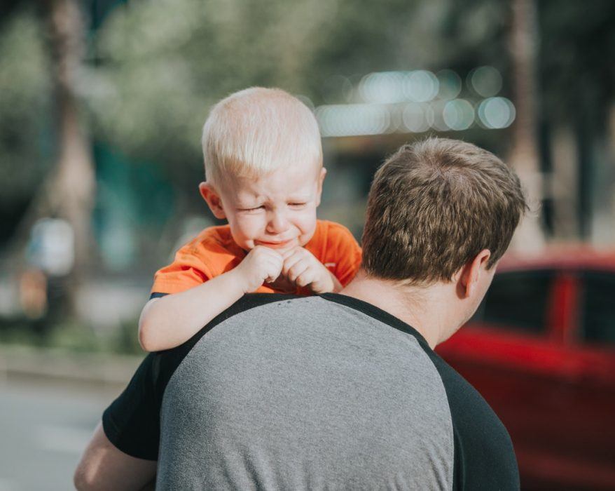 Tata niosący płaczące dziecko