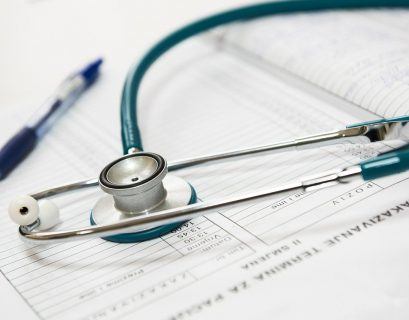 Stetoskop i długopis leżący na kartotece.